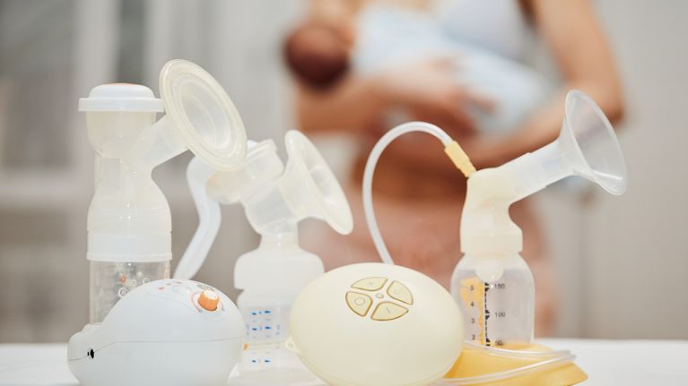 different breast pumps on background of mother holding child. 