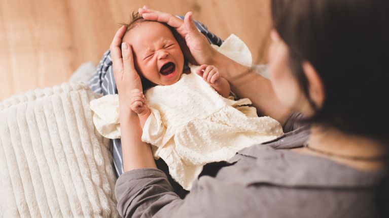 Woman with sick crying baby on hands wake up