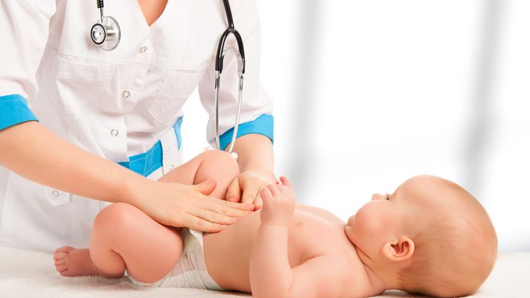 A Doctor examines and massaging baby tummy